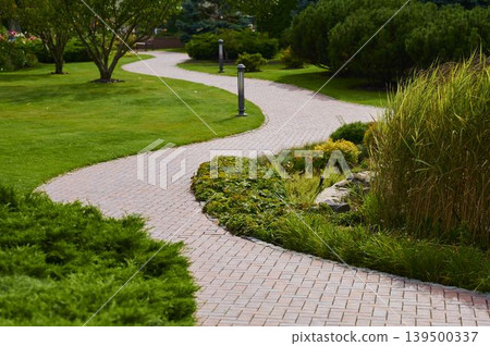 Winding brick path through a lush garden invites peaceful exploration on a sunny day Winding brick path through a lush garden invites peaceful exploration on a sunny day 139500337