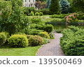 Delightful garden path through lush greenery and vibrant blooms on a sunny day 139500469