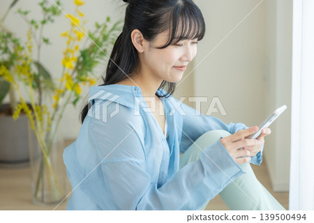 Young woman using a smartphone in a room Young woman using a smartphone in a room 139500494