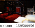 Antique-style chairs upholstered in red velvet line the shelves of a traditional coffee shop. 139500956