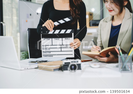 Creative team planning video production in modern office, using clapperboard, laptop and notebook. Business, marketing, content creation Creative team planning video production in modern office, using clapperboard, laptop and notebook. Business, marketing, content creation 139501634