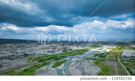 A cloudy May day, showing the Kurobe River alluvial fan and surrounding facilities such as Aimoto Bridge and parks, where it looks like it might rain. 139502356