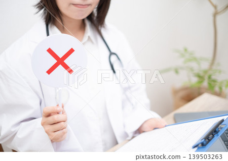 一位女醫生舉起一塊牌子,表示答案錯誤。 一位女醫生舉起一塊牌子,表示答案錯誤。 139503263