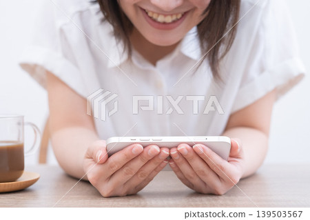 A woman smiling and holding her smartphone horizontally. A woman smiling and holding her smartphone horizontally. 139503567