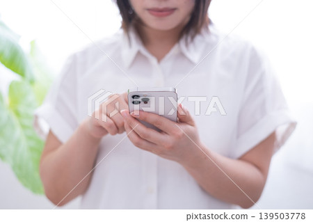 A woman operating a smartphone (front view) A woman operating a smartphone (front view) 139503778