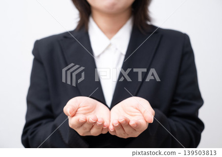 A woman in a suit with both hands outstretched. 139503813