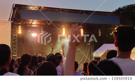The live music venue at night is buzzing with excitement as people point to the stage. The live music venue at night is buzzing with excitement as people point to the stage. 139503919