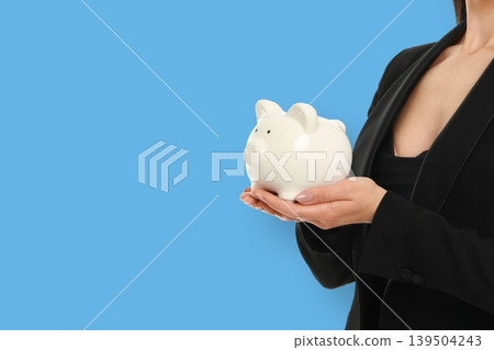 Woman stands with a piggy bank while working in finance Woman stands with a piggy bank while working in finance 139504243
