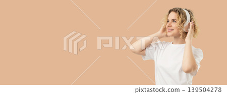 Woman smiles while wearing headphones and enjoying music Woman smiles while wearing headphones and enjoying music 139504278