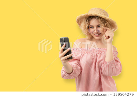 Woman holds smartphone with a smile while wearing a hat Woman holds smartphone with a smile while wearing a hat 139504279