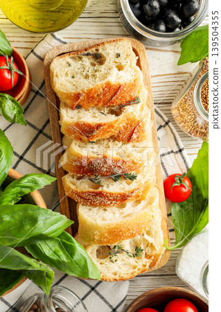 Freshly sliced bread on a wooden board with vegetables around it Freshly sliced bread on a wooden board with vegetables around it 139504355