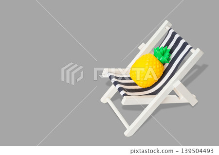 Pineapple sits on a small striped chair in a simple spot Pineapple sits on a small striped chair in a simple spot 139504493