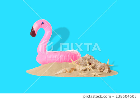 Flamingo float resting on sand with seashells nearby Flamingo float resting on sand with seashells nearby 139504505