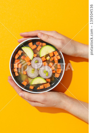 Hands hold a bowl of vibrant vegetable soup 139504536