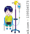 An image of a child sitting in a chair with an IV drip in their left arm, smiling and chatting while holding a tablet. 139504573
