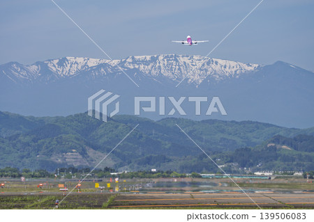 Sendai Airport on a sunny day: Zao mountain range and a plane taking off. Natori City, Miyagi Prefecture. 139506083