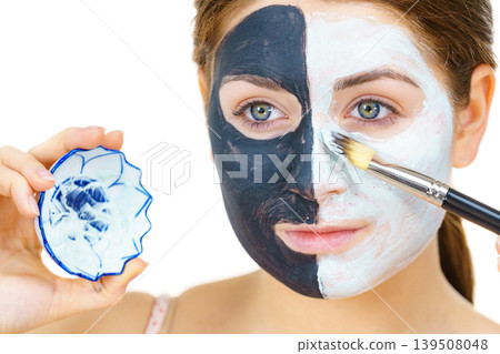 Girl black mask on half face apply white mud Girl black mask on half face apply white mud 139508048