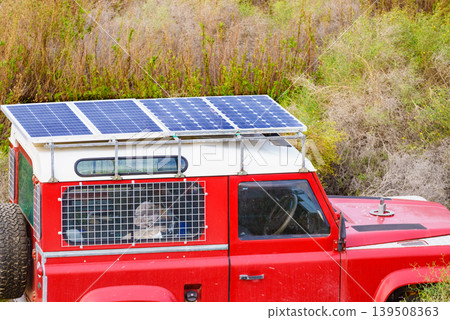 Red off road car with solar panels on the roof camping in a natural area. Red off road car with solar panels on the roof camping in a natural area. 139508363