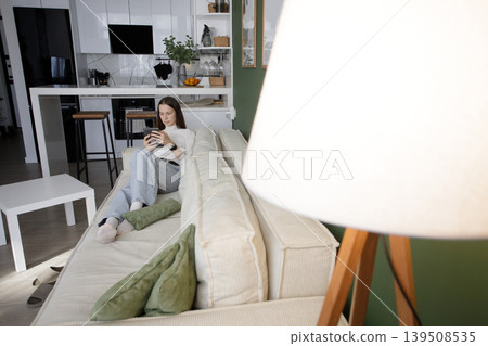 Cute woman using digital reader electronic book at home. Beautiful model with long hair Cute woman using digital reader electronic book at home. Beautiful model with long hair 139508535