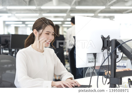 一位微笑的女商人正在一間免費辦公地址的辦公室工作。 139508971