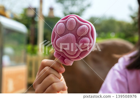 paw shaped grape ice cream on girl hand at amusement park 139508976