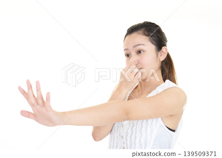 A woman makes a stop gesture while holding her nose. A woman makes a stop gesture while holding her nose. 139509371