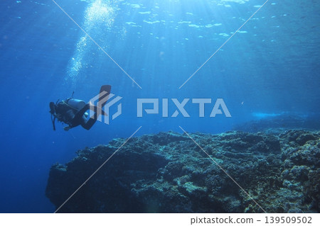Underwater photography of divers swimming among the coral reef at Otokoiwa Rock on Zamami Island. 139509502