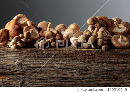 Fresh shiitake, champignon, and shimeji mushrooms on an old wooden table. 139510649