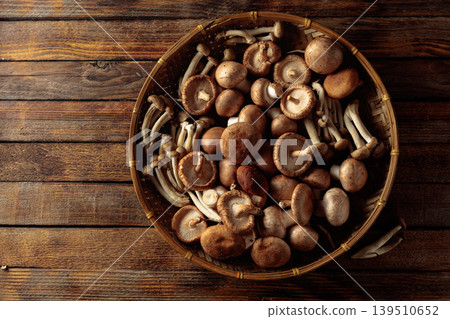 An assortment of mushrooms on a rustic wooden board. 139510652