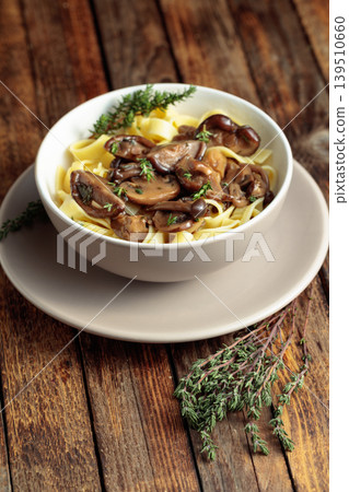 Noodles with mushrooms and thyme on a rustic wooden table. Noodles with mushrooms and thyme on a rustic wooden table. 139510660