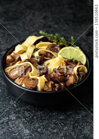 Noodles with mushrooms and thyme on a black stone table. Noodles with mushrooms and thyme on a black stone table. 139510663
