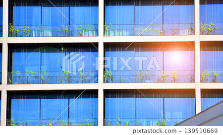 Sustainable glass office building with trees for reducing carbon dioxide. Eco-friendly building in modern city. Office with green environment. Corporate building reduce CO2. Sustainable glass office building with trees for reducing carbon dioxide. Eco-friendly building in modern city. Office with green environment. Corporate building reduce CO2. 139510669