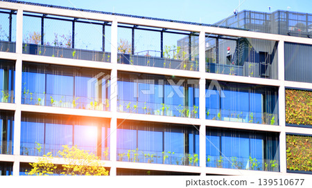Sustainable glass office building with trees for reducing carbon dioxide. Eco-friendly building in modern city. Office with green environment. Corporate building reduce CO2. Sustainable glass office building with trees for reducing carbon dioxide. Eco-friendly building in modern city. Office with green environment. Corporate building reduce CO2. 139510677
