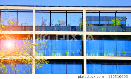 Sustainable glass office building with trees for reducing carbon dioxide. Eco-friendly building in modern city. Office with green environment. Corporate building reduce CO2. Sustainable glass office building with trees for reducing carbon dioxide. Eco-friendly building in modern city. Office with green environment. Corporate building reduce CO2. 139510693