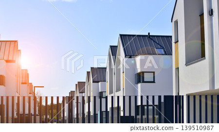 Terraced family homes in newly developed housing estate. The real estate market in the suburbs. New single family houses in a new development area. Residential homes with modern facade.  139510987