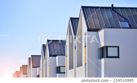 Terraced family homes in newly developed housing estate. The real estate market in the suburbs. New single family houses in a new development area. Residential homes with modern facade.  139510995