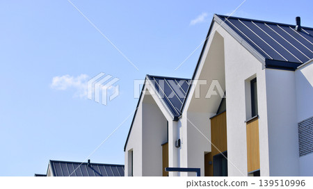 Terraced family homes in newly developed housing estate. The real estate market in the suburbs. New single family houses in a new development area. Residential homes with modern facade.  139510996