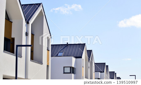 Terraced family homes in newly developed housing estate. The real estate market in the suburbs. New single family houses in a new development area. Residential homes with modern facade.  139510997