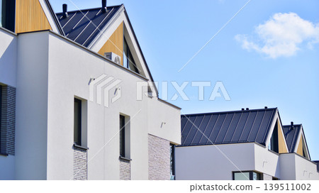 Terraced family homes in newly developed housing estate. The real estate market in the suburbs. New single family houses in a new development area. Residential homes with modern facade.  139511002