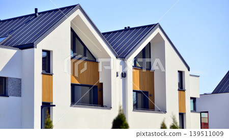 Terraced family homes in newly developed housing estate. The real estate market in the suburbs. New single family houses in a new development area. Residential homes with modern facade.  139511009