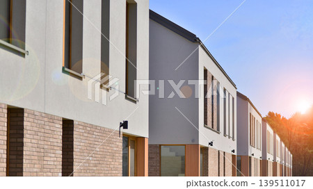 Terraced family homes in newly developed housing estate. The real estate market in the suburbs. New single family houses in a new development area. Residential homes with modern facade.  139511017