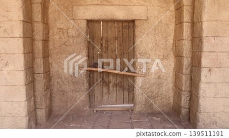 Weathered wooden door set in rough stone wall Weathered wooden door set in rough stone wall 139511191
