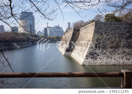 The stone walls and moat of Osaka Castle viewed through the leafless branches. The stone walls and moat of Osaka Castle viewed through the leafless branches. 139511245