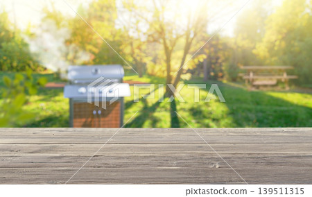 summer time in backyard garden with grill BBQ, wooden table, blurred background 139511315