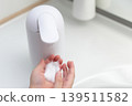 Toddlers washing their hands with a hand dispenser 139511582