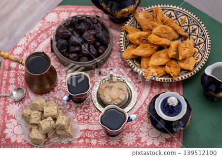 Oriental sweets and coffee on the table. Baklava, halva for dessert. Food and drink drink in cezve. Dates fruit Oriental sweets and coffee on the table. Baklava, halva for dessert. Food and drink drink in cezve. Dates fruit 139512100