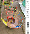 High angle view of a colorful metal merry-go-round and playground equipment on a dirt ground 139512206