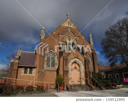 A brick church adorned with stained glass—a refined Gothic landscape with striking stone arches. A brick church adorned with stained glass—a refined Gothic landscape with striking stone arches. 139512995