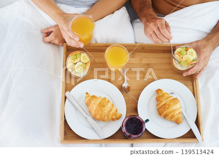 Couple, food and breakfast in bed for morning, wakeup or meat and snack together in relax at home. Top view of man and woman hands eating healthy for diet, nutrition or vitamin c juice in bedroom 139513424