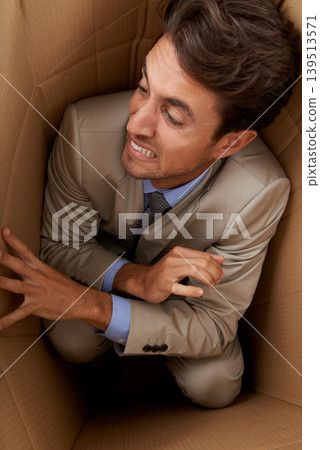 Businessman, trapped and box at work with stress, scared and fear in office for career or startup. Entrepreneur, corporate and person isolated in cardboard at workplace with frustrated and anxiety Businessman, trapped and box at work with stress, scared and fear in office for career or startup. Entrepreneur, corporate and person isolated in cardboard at workplace with frustrated and anxiety 139513571